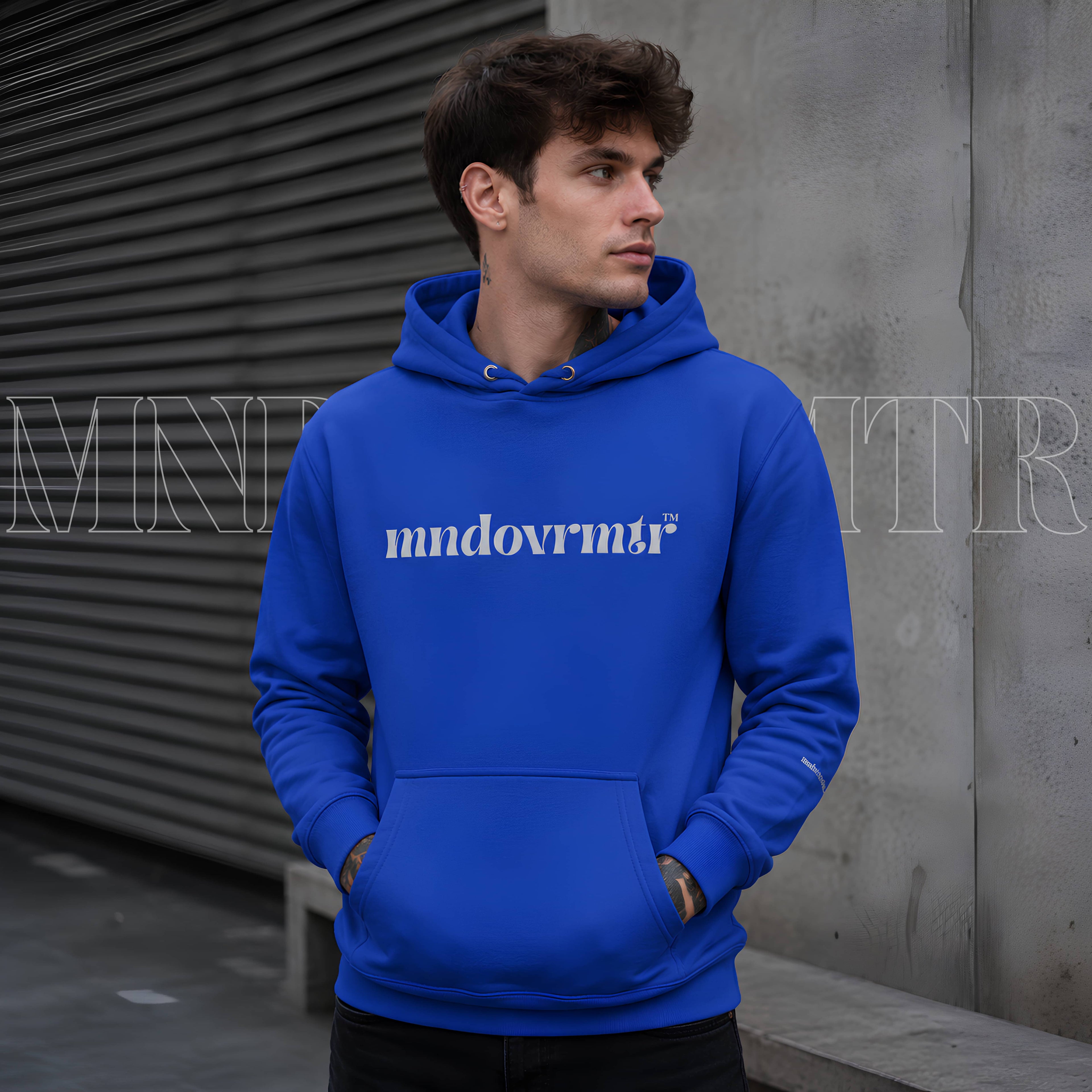 A beautiful man, wearing a Royal Blue, cotton, fleece, oversized, hoodie with a front pocket , designed by a gray "mndovrmtr" text across the chest 