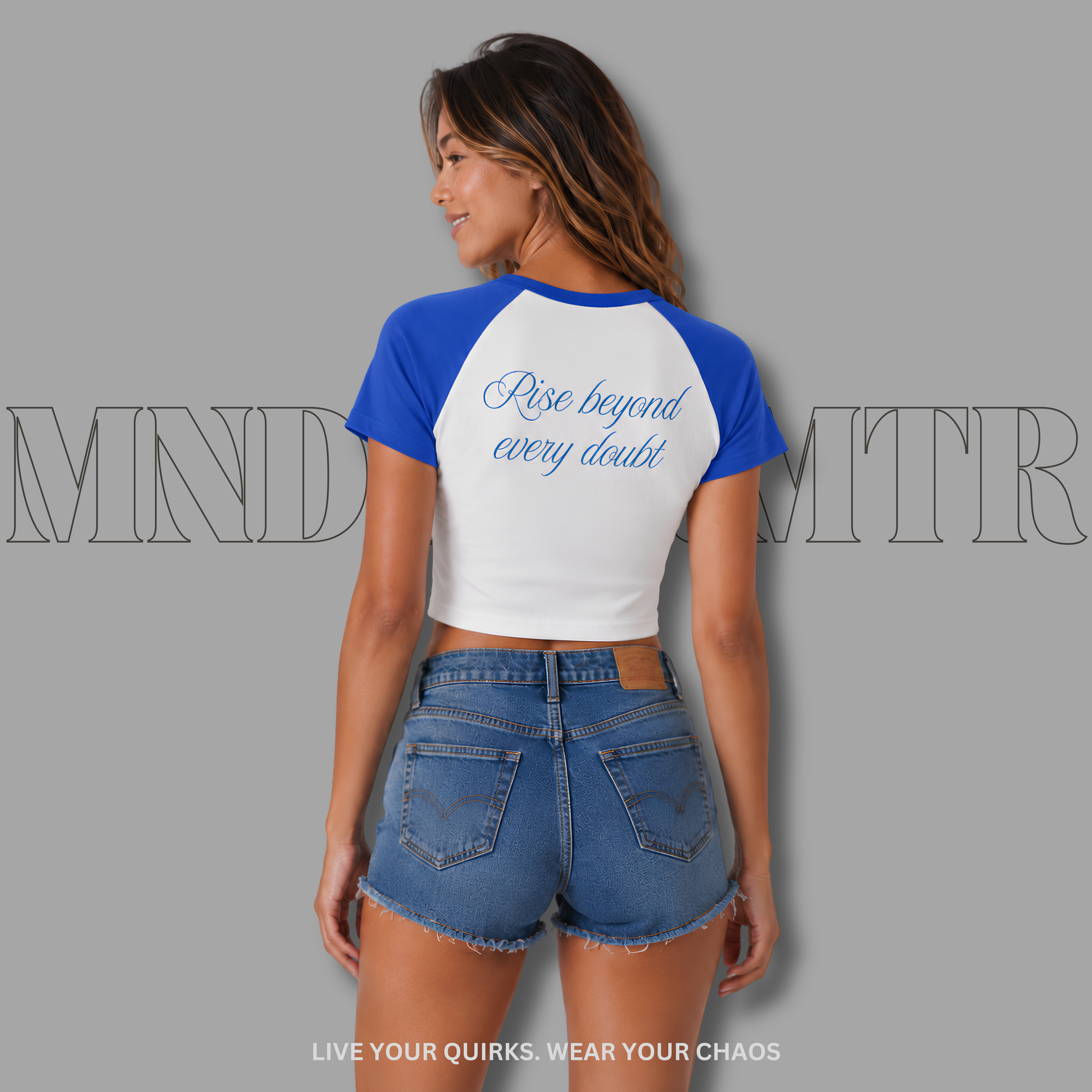 Woman wearing a white and royal blue crop baseball shirt with 'Rise beyond every doubt' text, against a gray background.