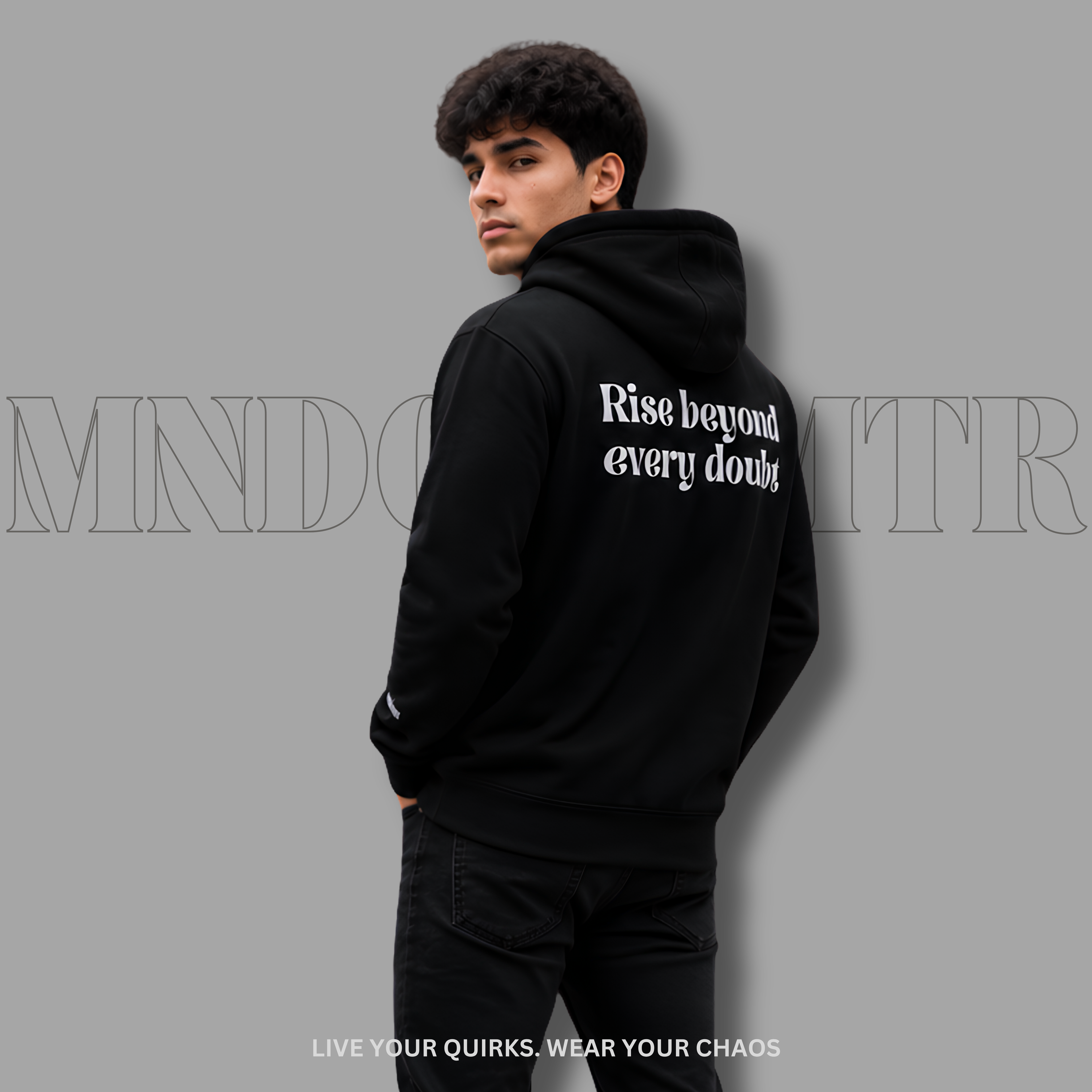 A man wearing a black fleece hoodie with the phrase 'Rise beyond every doubt' printed in grey, brasika font style text on the back, shown from a three-quarter back view against a solid gray background.