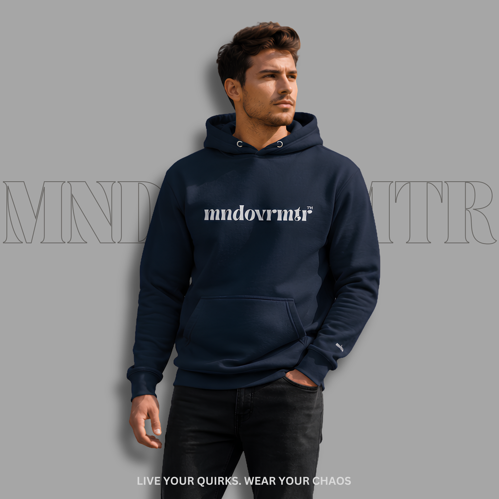 A man wearing a navy blue, fleece, hoodie with 'mndovrmr' printed in grey across the chest, paired with black jeans, set against a solid gray background with a faint brand watermark.