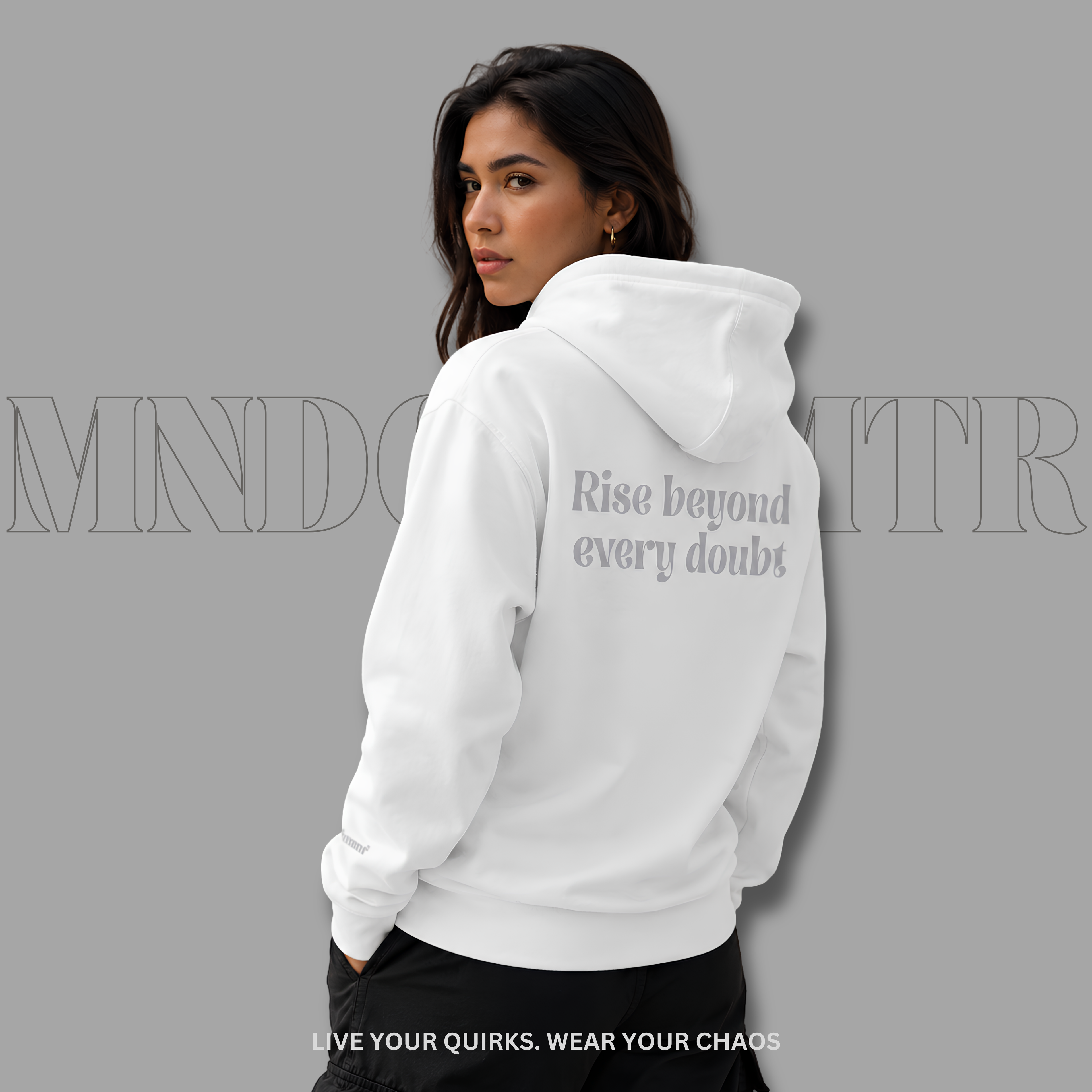 A woman shown from the back wearing a white, oversized, cotton, fleece, hoodie with the text 'Rise beyond every doubt' printed in gray on the back, against a solid gray background.