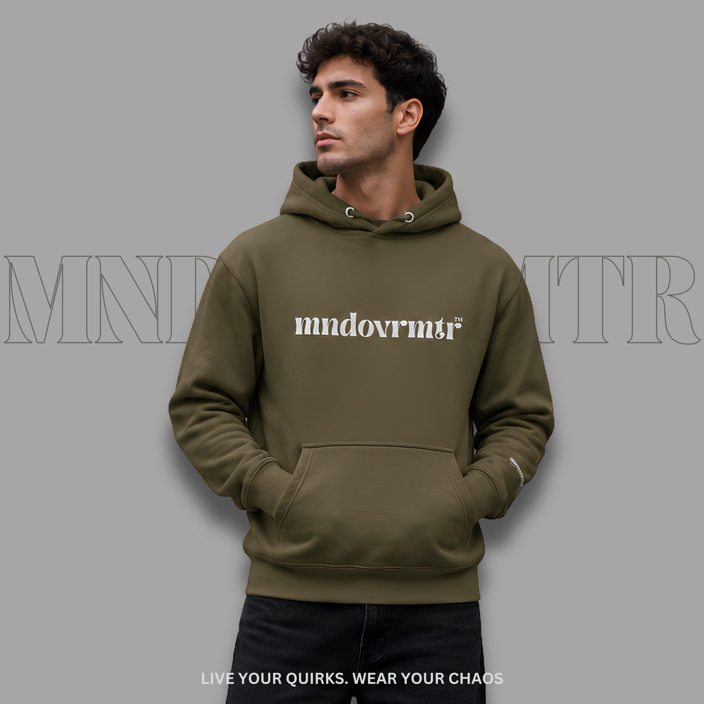 A man wearing an military green, oversized, fleece, hoodie with  front pocket and 'mndovmrtr' text printed in grey across the chest, posed against a solid gray background with a faint brand watermark.