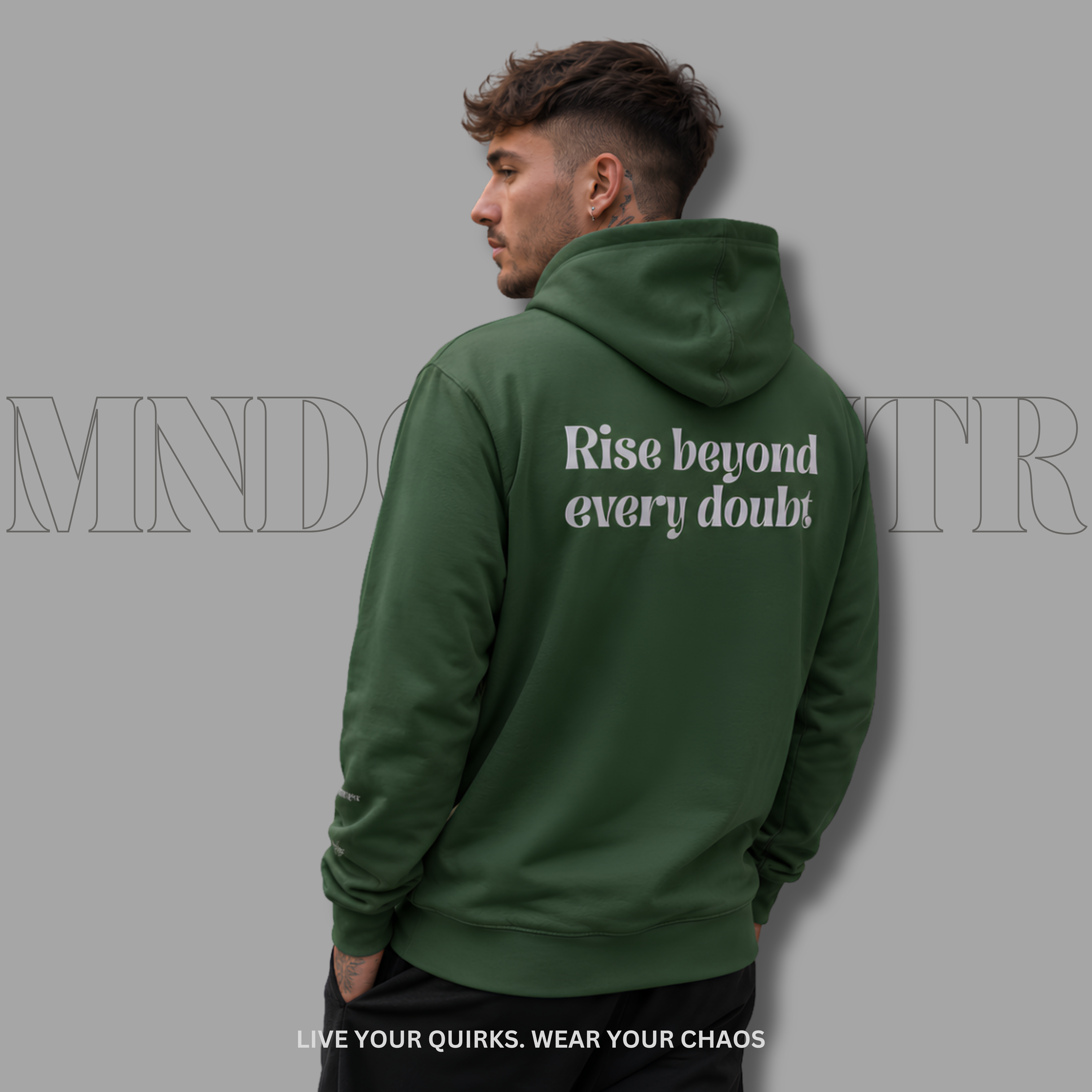A man wearing an forest green hoodie from the back, featuring the gray text 'Rise beyond every doubt' printed on the back. The image is set against a solid gray background with a faint watermark and text at the bottom.