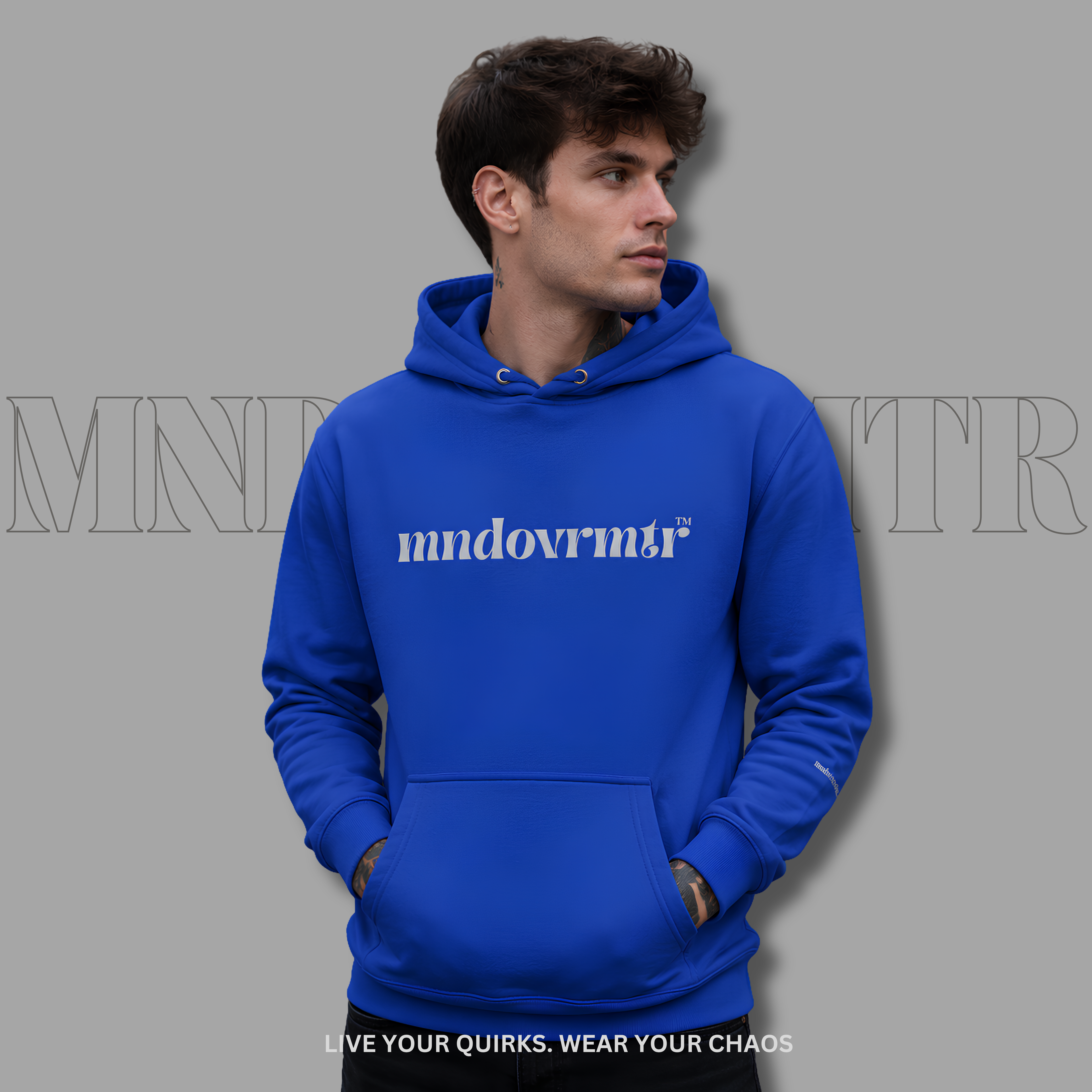 A man wearing a bright royal blue fleece hoodie with the word 'mndovrmtr' printed in grey across the chest, posed against a solid gray background with a faint brand watermark.