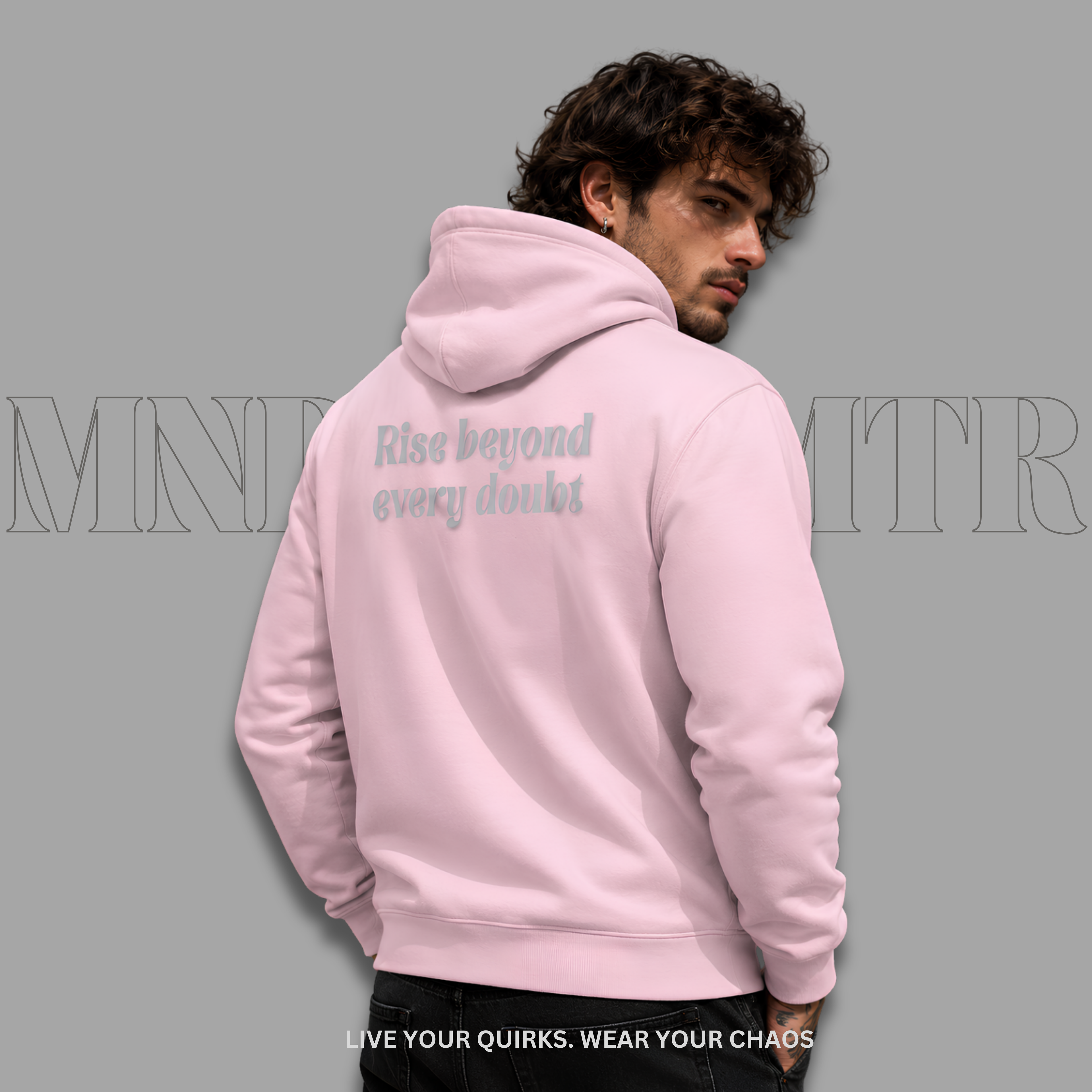 A man wearing a light pink, cotton, fleece, hoodie, shown from the back, featuring the text 'Rise beyond every doubt' printed in a light gray script on the back. The background is a solid gray with a faint watermark.