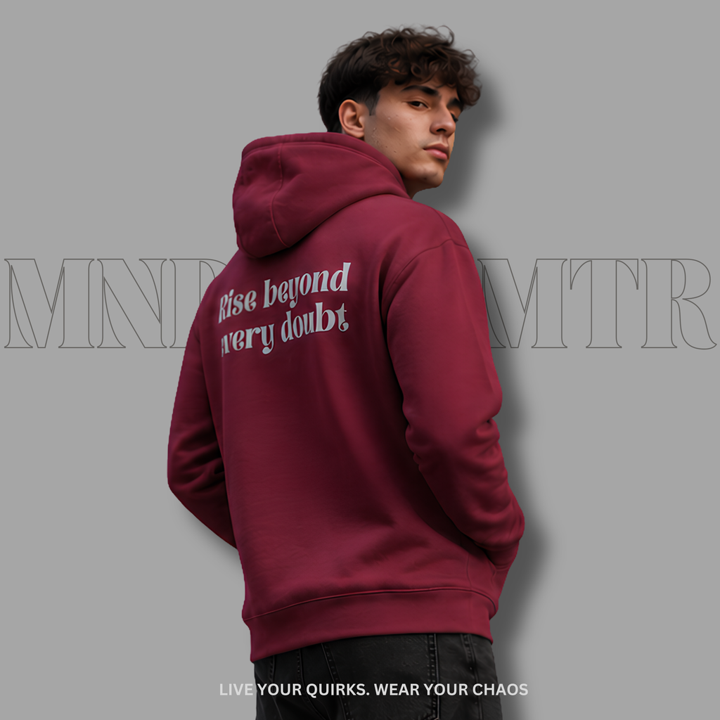 A young adult man wearing a maroon, cotton, fleece, oversized, hoodie with gray  text on the back reading 'Rise beyond very doubt', shown from the back against a solid gray background.