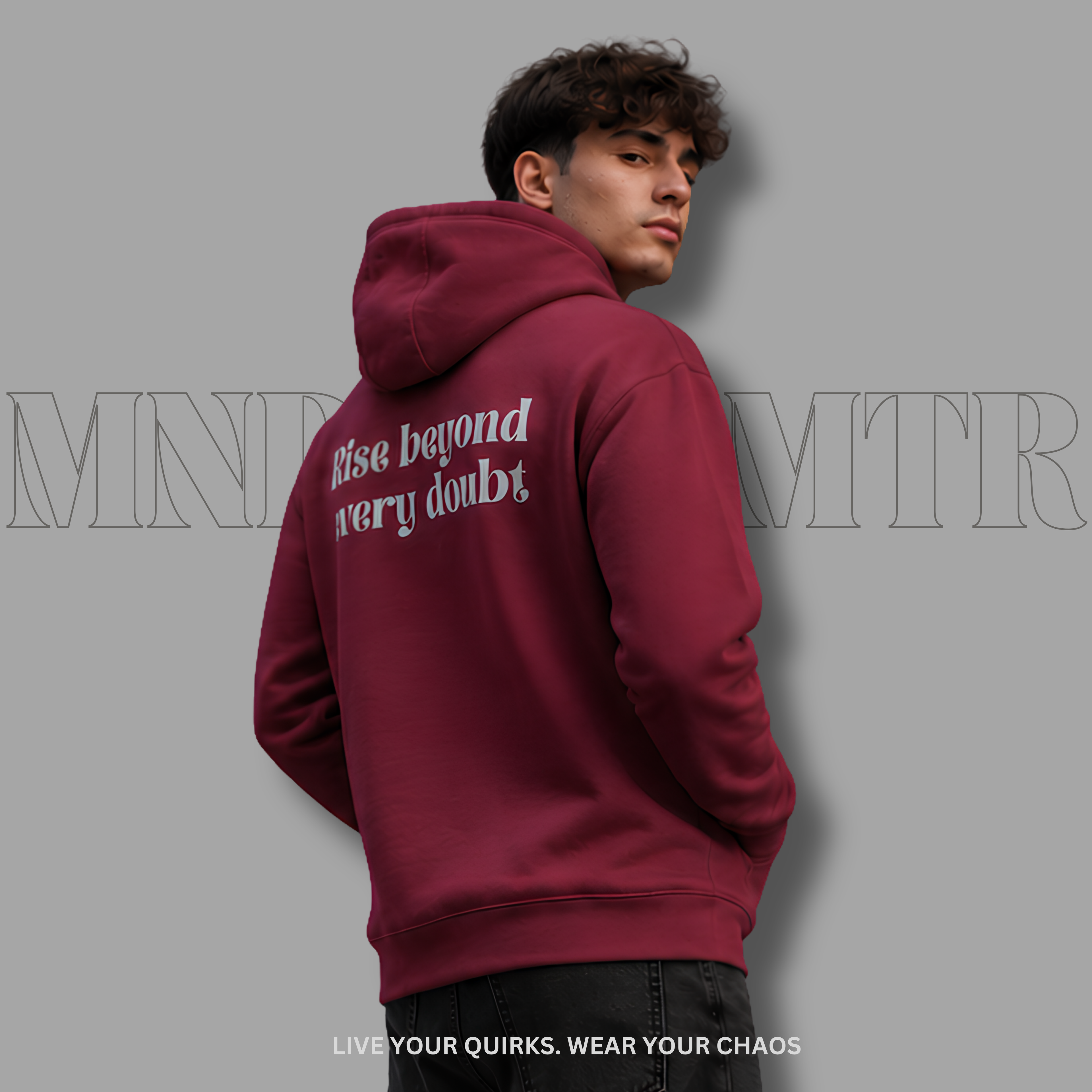 A young adult man wearing a maroon, cotton, fleece, oversized, hoodie with gray  text on the back reading 'Rise beyond very doubt', shown from the back against a solid gray background.
