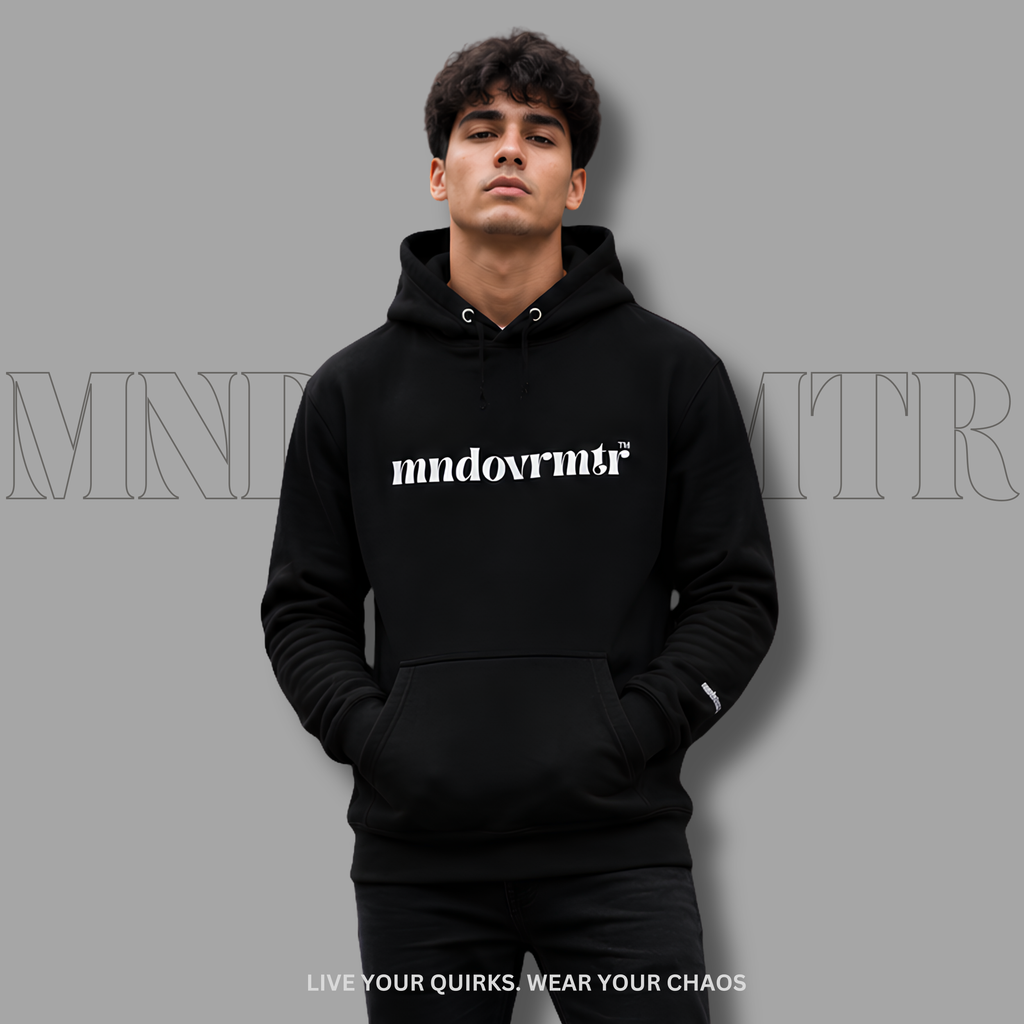A man wearing a black pullover hoodie with the word 'mndovrmr' printed in grey across the chest, posed against a solid gray background with a faint brand watermark.